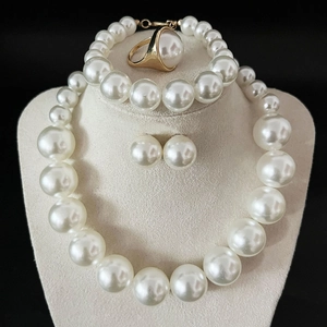 Detailed set of large pearl necklace, bracelet, studs and ring on beige velvet display