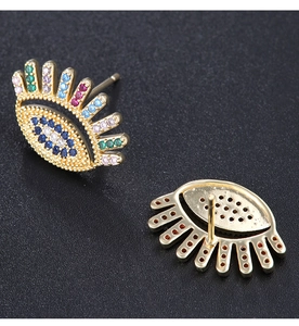 Detailed close-up of golden evil eye earrings with colorful rhinestones on black background