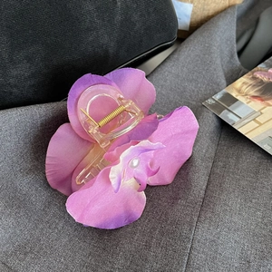Macro detail of purple orchid hair claw clip with silk petals and pearl centerpiece