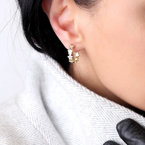 Elegant gold hoop earrings with star charms and zircon stones worn for winter style
