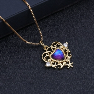 Detail eines goldenen Herzanhängers mit lila-blauem Kristall und hohlem Muster