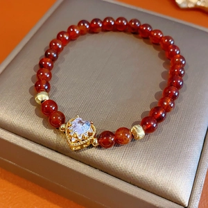 Detail of garnet red agate bracelet with gold heart pendant on jewelry box display