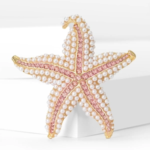 Macro detail of starfish brooch with warm gold base, white pearls and pink rhinestones