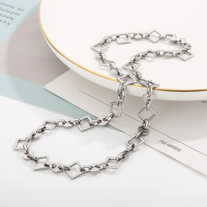 Detail of silver geometric square and round link chain necklace on white jewelry plate
