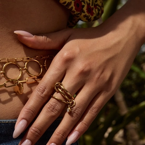 Macro shot of gold multi-layer rings with zircons and matching metal waist chain