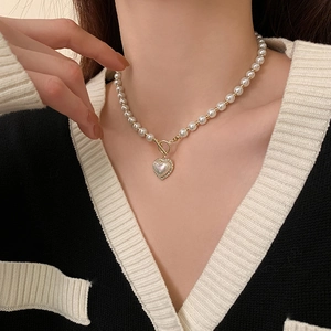 Detail of a pearl heart pendant necklace with gold OT toggle clasp on a female model