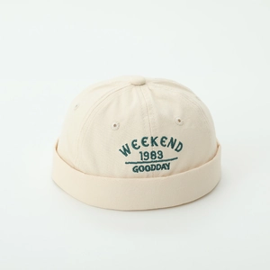 Close-up of beige cotton docker hat with green Weekend 1983 embroidery for boys