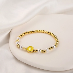 Détail macro du bracelet à perles dorées avec perles et breloque main de Hamsa sur un plateau