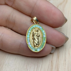 Gold oval religious pendant with embossed figure and green iridescent shell inlay