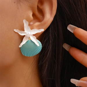Detail of beach-inspired starfish and seashell earring with faux pearl on a model