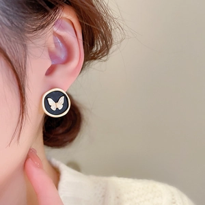 Macro detail of vintage black and gold round butterfly stud earring on model