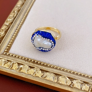 Macro detail of vintage gold-plated ring with baroque pearl, blue rhinestones and crystals