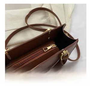 Detail view of smooth metal zipper and golden hardware on a brown faux leather handbag