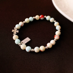 Macro detail of handmade beaded bracelet with blue stone beads and clover charm