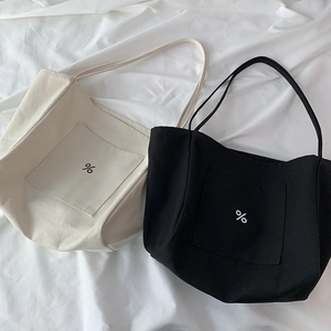 Detailed view of canvas tote bags in cream and black featuring a stylish percent sign logo
