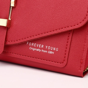 Close-up of red lychee leather texture with golden hardware on a women's phone wallet