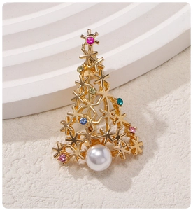 Close-up of golden Christmas tree brooch with white pearl and colorful rhinestones