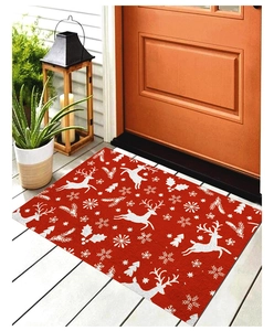 Détail du paillasson de Noël rouge avec motifs de renne et de flocons sur un porche