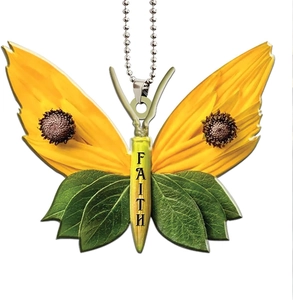 Detail of acrylic butterfly ornament with sunflower pattern and FAITH text on white background