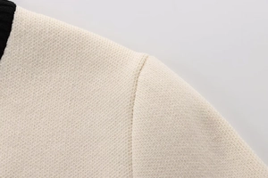 Detail of the cream knit sweater with contrast black ribbed collar and shoulder seams