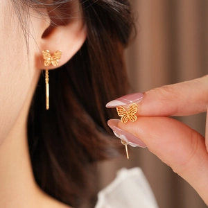 Detail of vintage gold plated butterfly threader earring featuring brushed metal texture