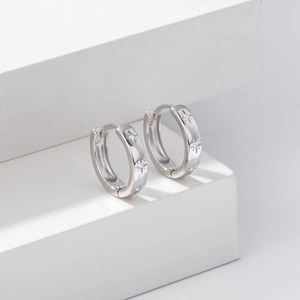 Detailed view of silver star earrings with micro-inlaid zircons on white display stand