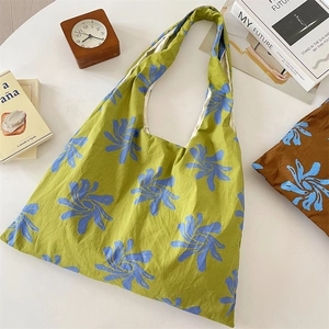 Detailed close-up of green canvas tote bag with blue floral print on white desk