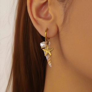 Gold-plated sea star and shell drop earrings with white pearl detail on model