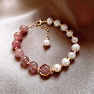 Detail of strawberry quartz beads and pearls with gold pendant on silk texture