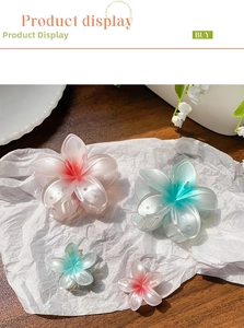 Detail view of pink and blue gradient frangipani flower hair claws in two sizes