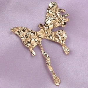 Macro view of gold butterfly pendant with unique wrinkled texture on purple silk