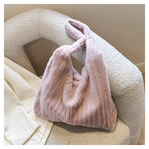 Close-up of pink faux fur tote bag with vertical stripes on a plush armchair