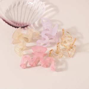 Close-up of four wavy jelly plastic hair claws in pink, lilac, beige, and amber colors
