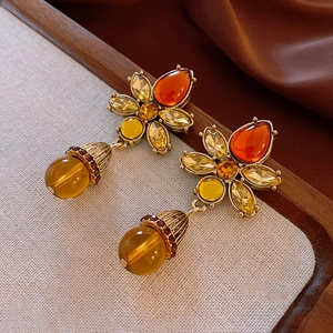 Detailed macro of vintage flower earrings with amber stones on elegant warm fabric