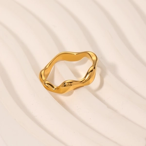 Minimalist gold wavy geometric stainless steel ring on elegant stone background