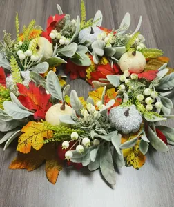 Detail of autumn wreath with maple leaves, frosted pumpkins, and berries on wood