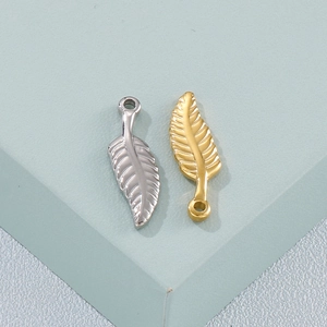 Golden and silver wing feather pendants made of metal on a geometric display stand
