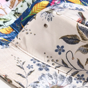 Dettaglio ravvicinato del cappello alla pescatora a fiori con occhielli metallici