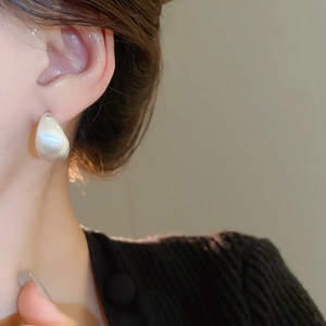 Detailed close-up of a minimalist waterdrop earring with a matte white satin finish