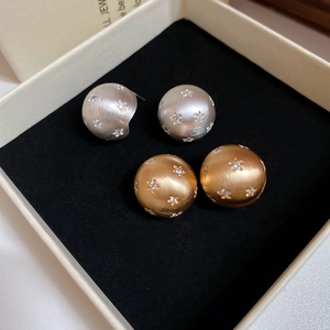 Detailed macro of matte brushed sphere stud earrings with star-shaped zircon inlays