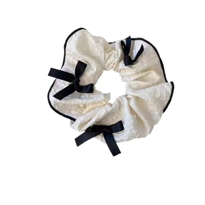 White pleated scrunchie with black trim and ribbon bows shown from a top view