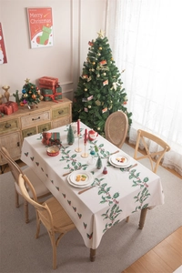 Detail of beige Christmas tablecloth with holly leaves, red berries, and tassel edges