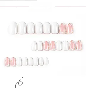 Detail of round white press-on nails with delicate floral patterns on a pink base