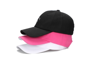 Détail de casquettes empilées noir, rose et blanc avec broderie coeur sur tissu en coton pur