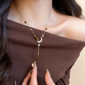 Close-up of gold moon and star pendant necklace with tiger eye beads and zircon stones