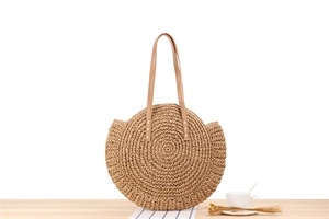 Detailed close-up showing texture of round straw woven shoulder bag with leather handles