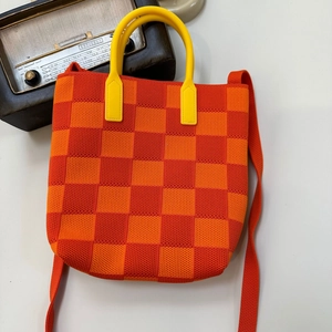 Close-up of orange checkerboard knit tote bag with yellow round handle and long strap