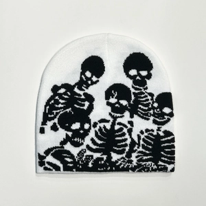 Close-up of a white knitted beanie featuring a detailed black skull pattern design