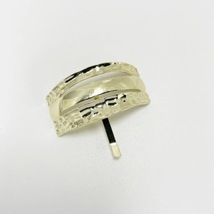 Detailed view of the gold U-shaped hair clip with hammer texture and smooth stripes