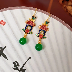 Detailed shot of 18K gold heart earrings with enamel pavilions on a white paper fan